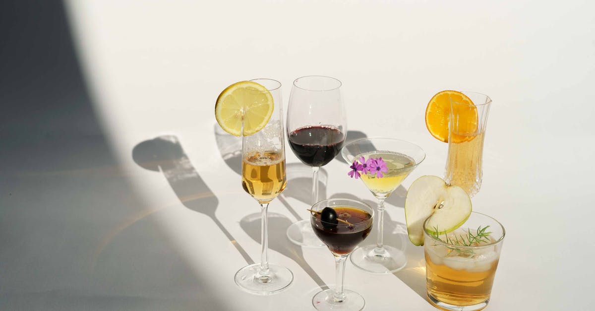 How do olive oils differ, and what should they be used for? - High angle of crystal glasses filled with champagne red wine Manhattan with olive on toothpick martini near pear calvados in white studio