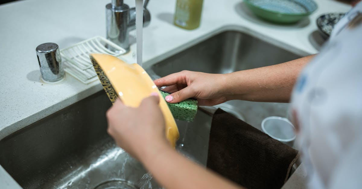 How do professional chefs keep food thermometers clean between uses? - Person Holding Yellow Plastic Container