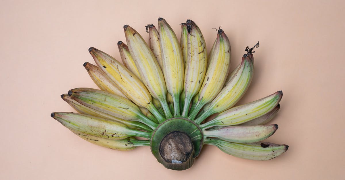 How do the nutritional values of bananas change as they ripen? - Top view composition of recently collected harvest of ripe fresh bananas placed on pink background