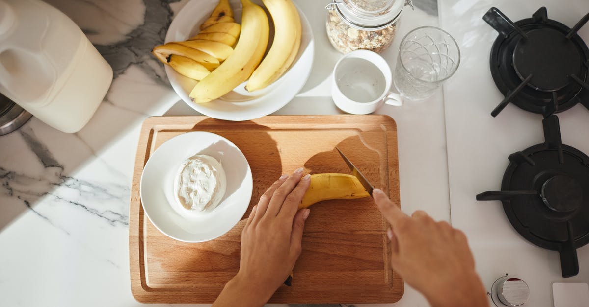 How do you funnel food off a cutting board? - A Hand Cutting the Banana on a Wooden Chopping Board