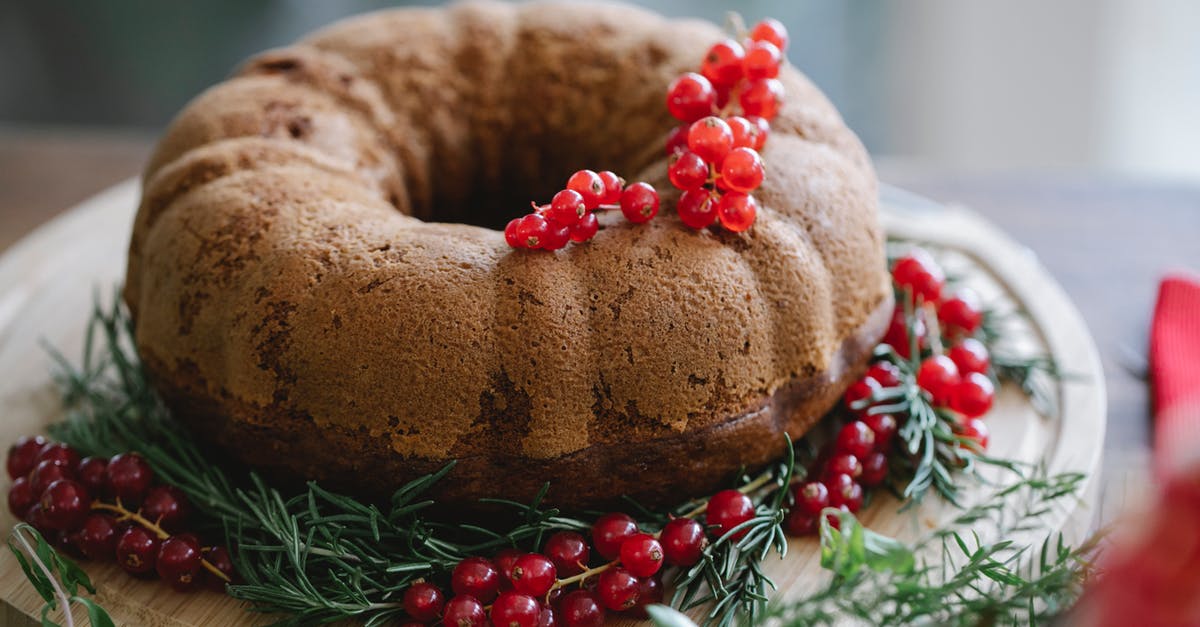 How do you make a cake with soft fillings baked inside? - Palatable cake with ripe red berry bundle near pine sprigs on wooden tray during New Year holiday