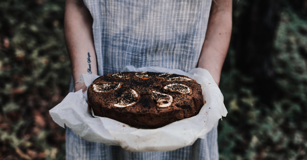 How do you make a cake with soft fillings baked inside? - Crop unrecognizable female with tattoo and tasty chocolate cake with lemon slices on top outdoors