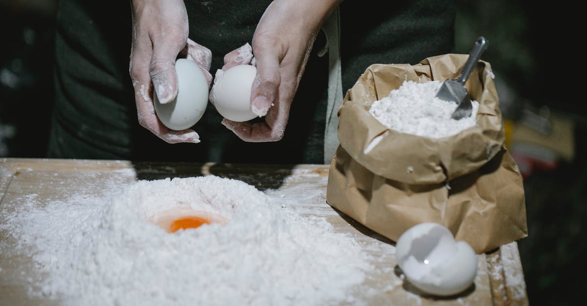 How do you make the wishbone break easier? - High angle of crop anonymous chef breaking eggs for cooking dough at table with flour