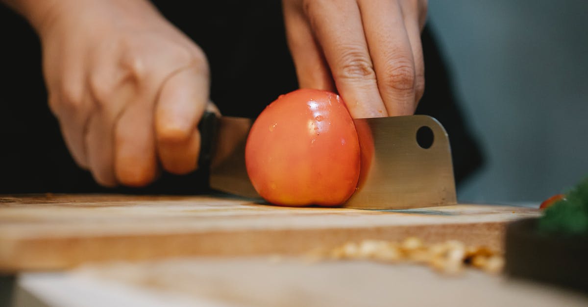 How do you properly clean a cutting board and knife to prevent cross contamination? - Cook cutting tomato on chopping board for recipe