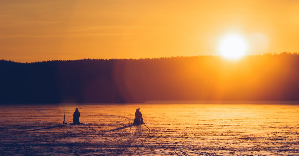 How do you properly defrost frozen fish? - Silhouette Of Two Persons Sitting While Snow Fishing On An Iced Covered Body Of Water At Dawn