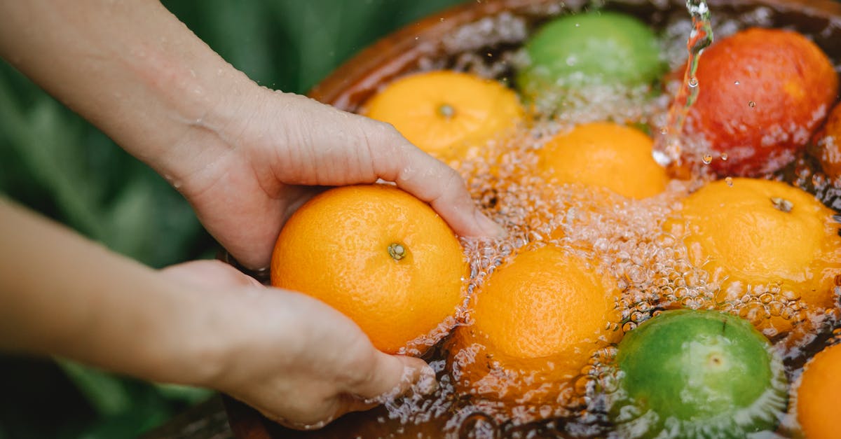 How do you properly wash hands after dealing with raw chicken? - Woman washing fruits in fresh water