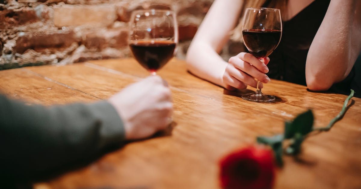 How do you reduce wine when deglazing without burning the fond? - Crop anonymous couple in elegant outfits enjoying romantic date in bar at table with red rose and glasses with wine near brick wall