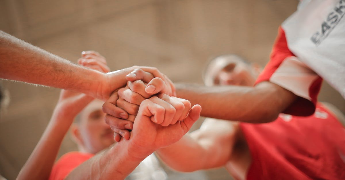 How do you separate the skin from pork? - From below of crop multiethnic team of professional basketball players gathering and putting hands together while standing on playground before game