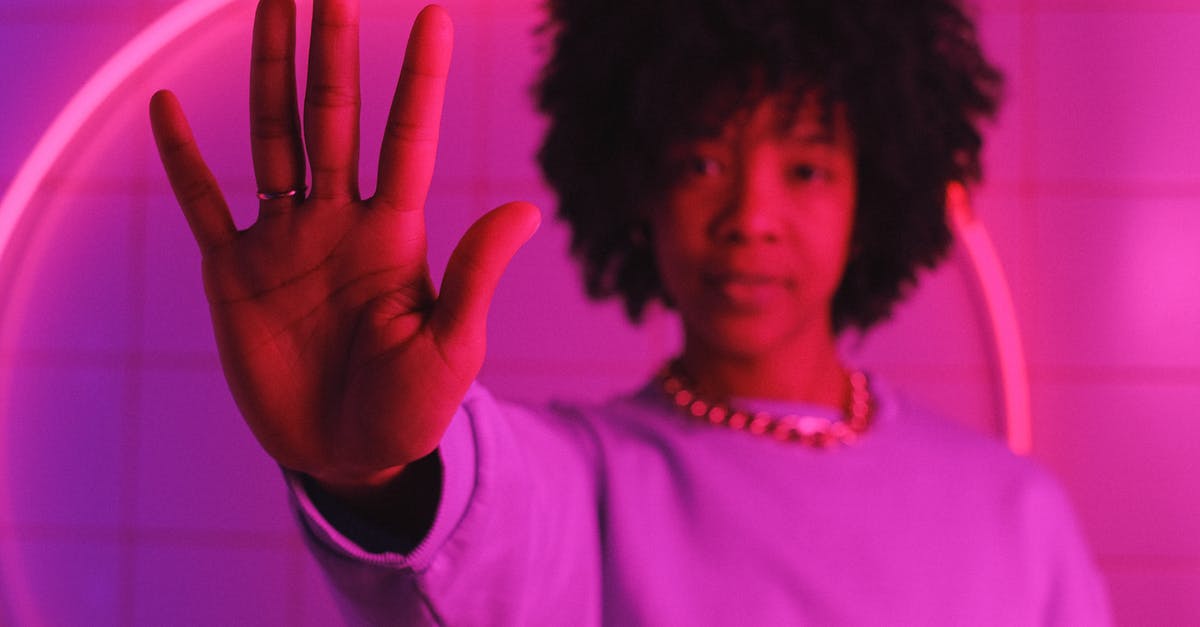 How do you stop limes from drying out? - Serious black woman standing with raised arm in room with pink illumination