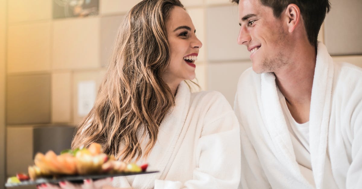How does cooking food changes its content of carbohydrates and sugar? - Side view of content couple in bathrobes relaxing on bed with platter of mixed fruit and looking at each other