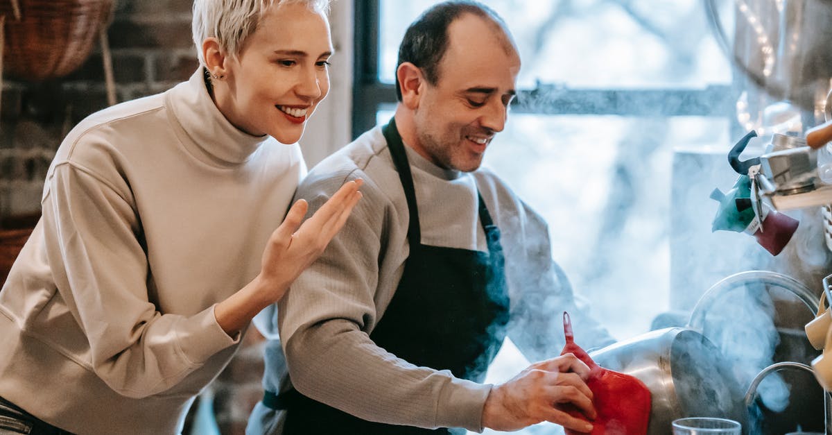 How does double-bagging sous vide food affect cook time? - Happy ethnic man preparing dinner for smiling wife in kitchen