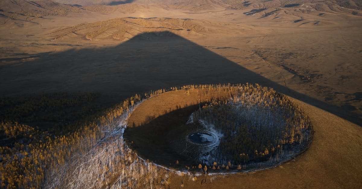 How does sourdough (wild yeast) starter differ from location to location? - Aerial view of Khorgo extinct volcano grown with forest and covered with snow casting huge dark shadow on valley in national park in Mongolia