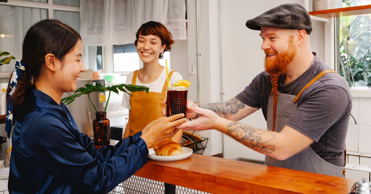 How does velveting work? - Glad hipster male employee passing glass of Black Velvet cocktail to smiling ethnic colleague at work