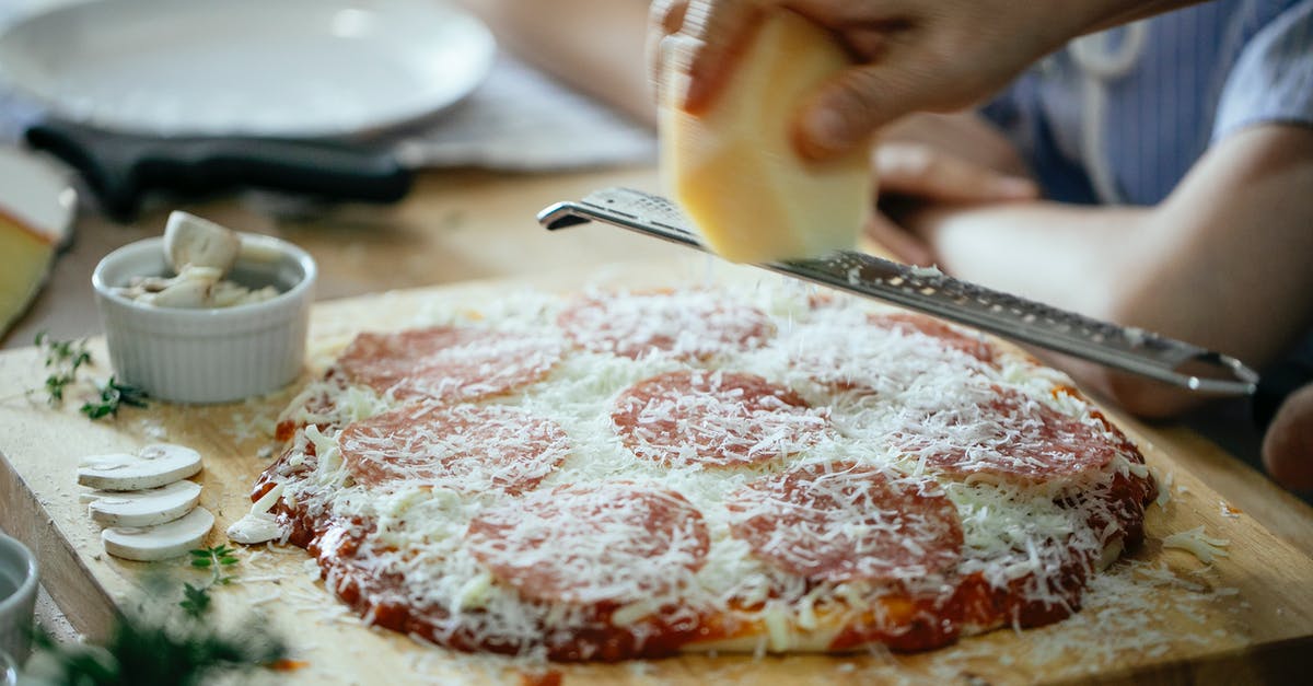 how early can I put food into a slow-cooker? - Unrecognizable person grating cheese on pizza