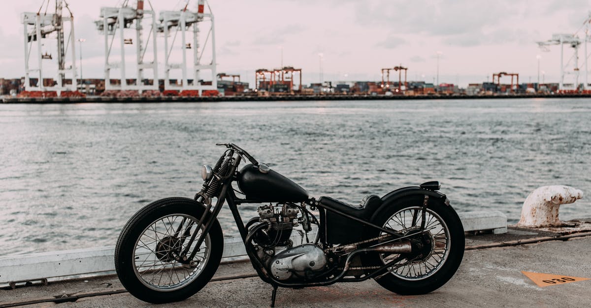 How fast does water cool off after boiling? - Vintage motorcycle on asphalt embankment near rippling river water against industrial area in city