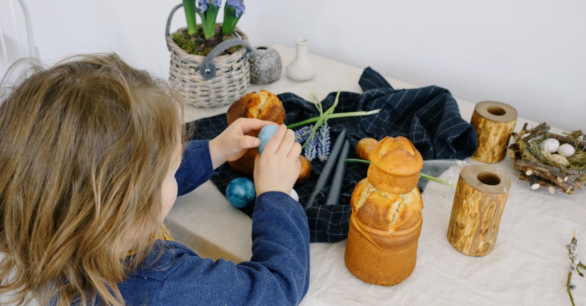 How important are eggs for a muffin recipe? - Little Girl Holding an Egg over a Table With Easter Decorations
