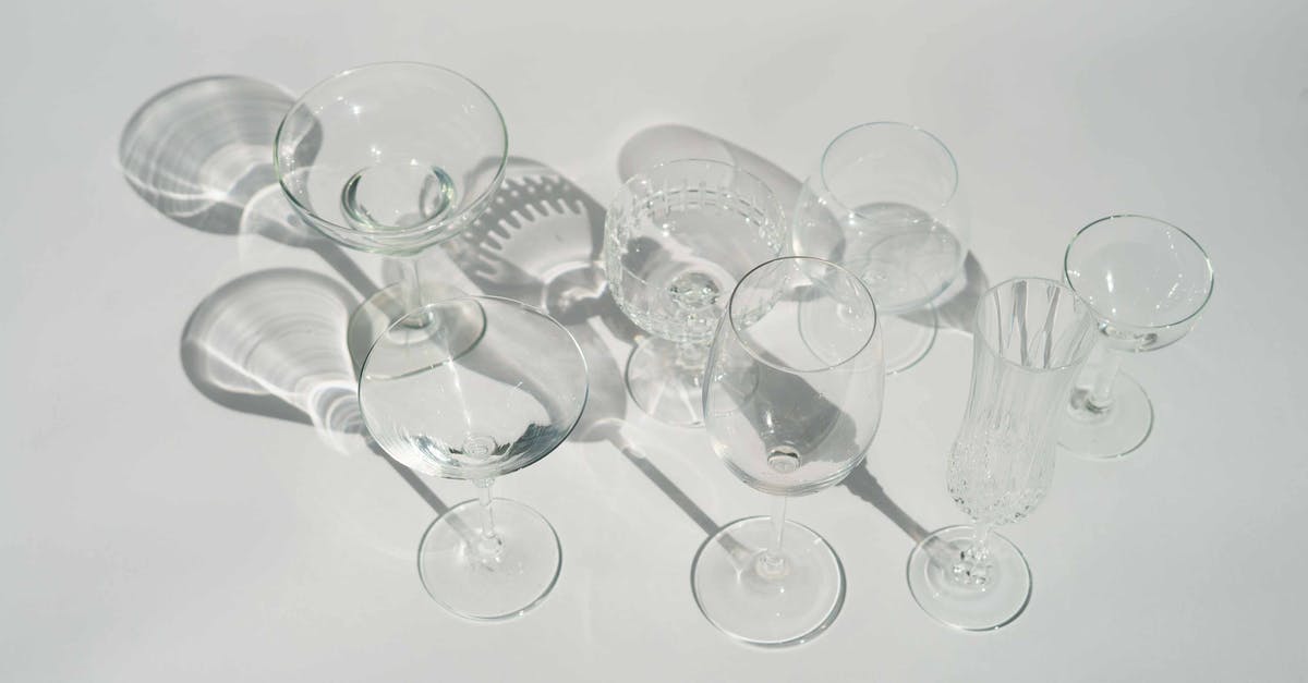 How is flambéing different from just adding alcohol? - High angle of transparent different glasses for various cocktails and beverages in white studio