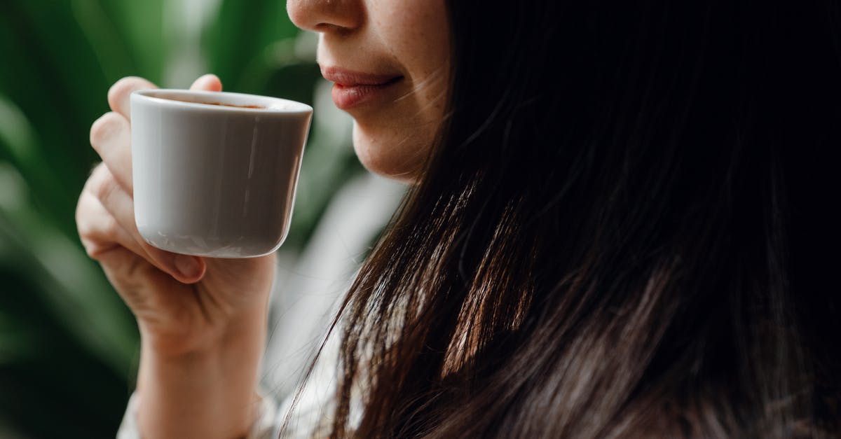 How long can I keep espresso in the fridge? [duplicate] - Crop long haired brunette drinking hot aromatic coffee from small ceramic cup in cafe against blurred green pot plants