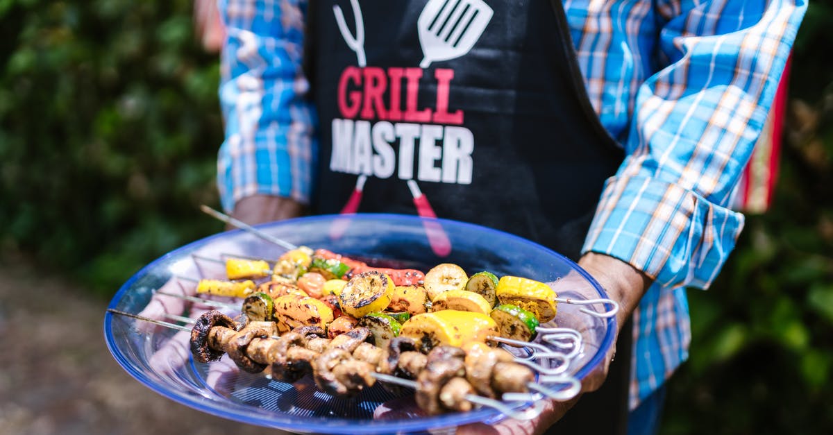 How long can my smoked brisket stay in holding? - A Person in Plaid Long Sleeves and Black Apron Holding a Glass Plate with Barbecue