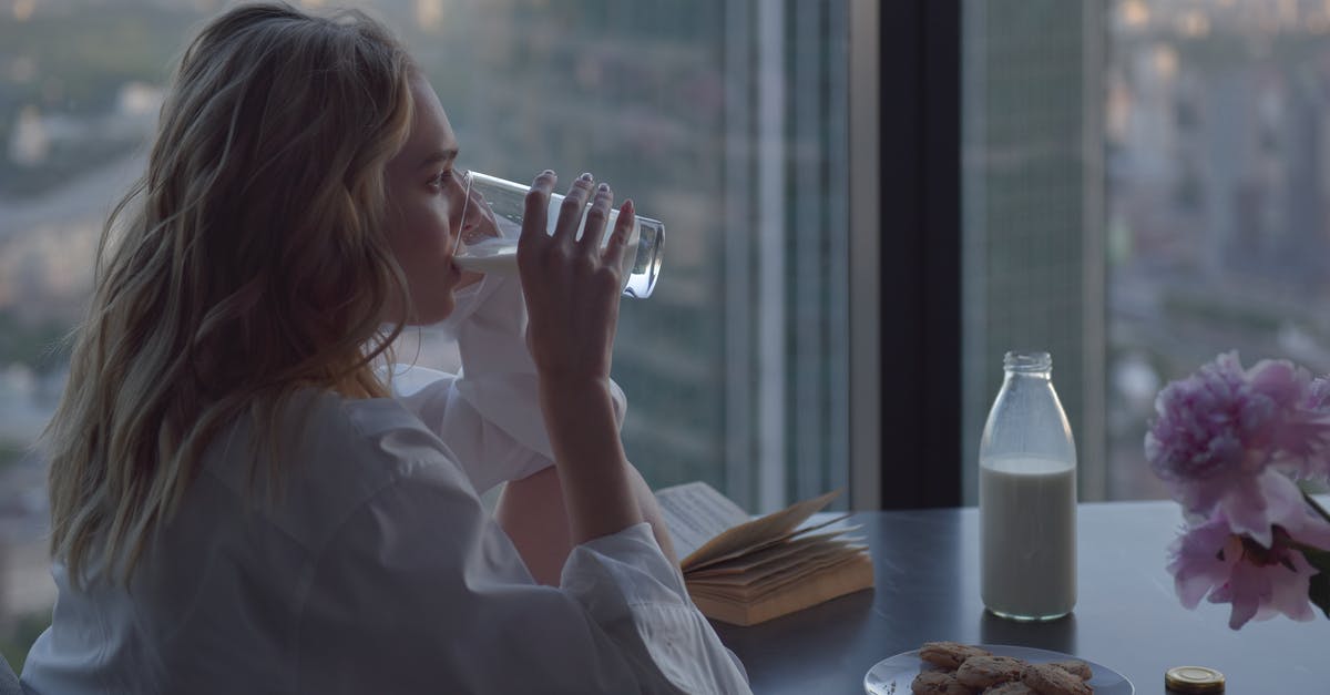 How long does it take for milk to spoil unrefrigerated? - A Woman in White Long Sleeves Drinking Milk and Sitting Near the Glass Windows