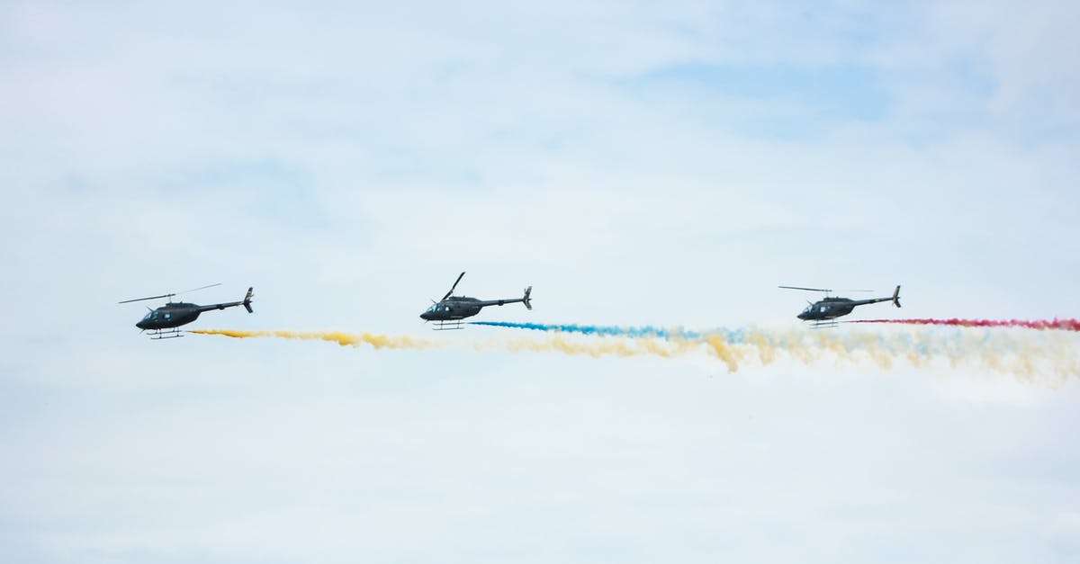 How long does it take to smoke a chicken? - From below of identical black helicopters with long tails and propellers flying in cloudy sky while leaving colorful wavy traces with smoke effect in daylight