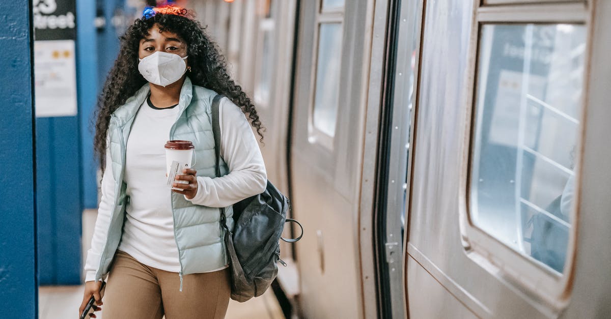 How long is coffee with creamer added safe in a thermos? - Calm black woman with coffee wearing medical mask standing in metro