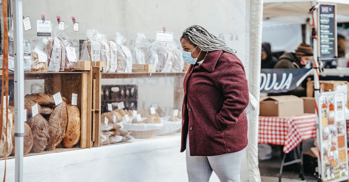 How long should bread dough warm up after cold fermentation? - Side view of adult African American woman wearing protective mask and warm coat walking in street market while selecting bakery products in daylight