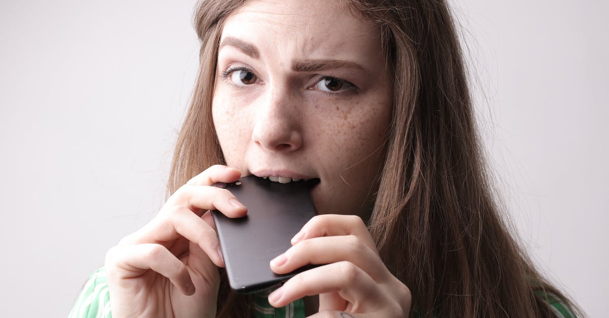 How long should I let a tea with lemongrass steep? - Nervous young female in casual clothing standing with cellphone in mouth after unpleasant phone call on gray background in studio