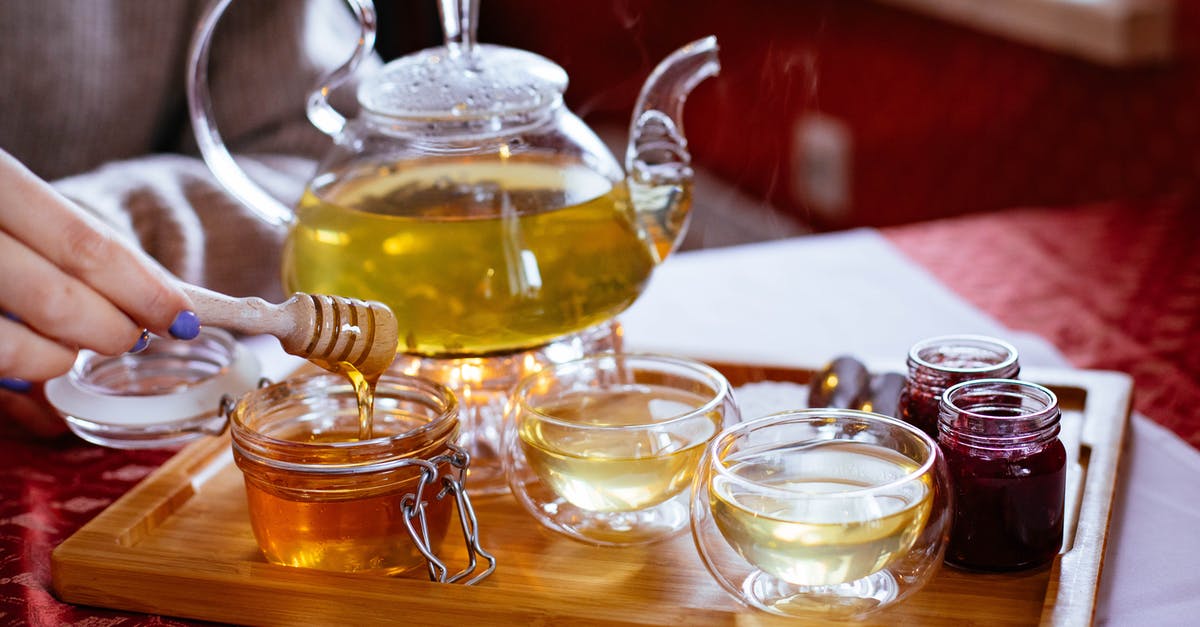 How long should I let my tea cool before adding unpasteurized honey to it? - Person Holding Honey Stick With Teapot