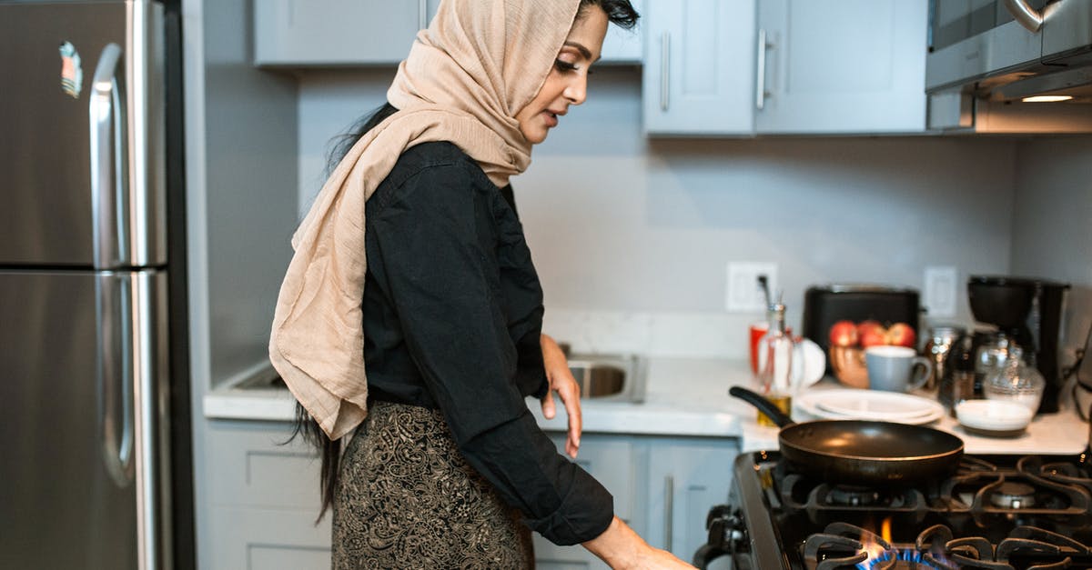 How long should I wait for my gas oven to heat up? - Ethnic woman in headscarf switching on stove How long should I wait for my gas oven to heat up? - Ethnic woman in headscarf switching on stove