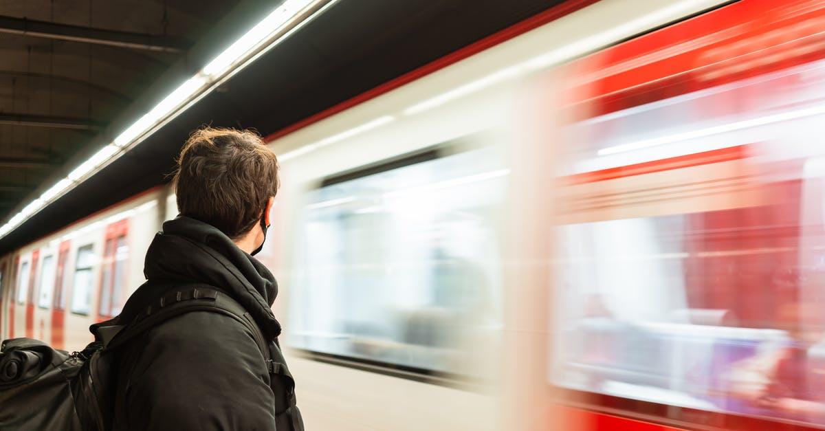 How long should I wait until I put new jars in? - Side view of faceless male passenger in protective mask wearing warm outerwear standing on platform of metro station near train