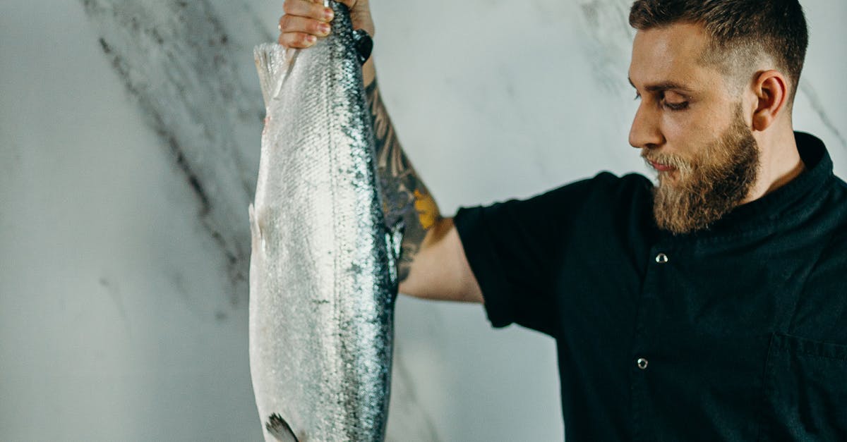 How long to cook seafood in paella? - Man Looking At A Big Fish He Is Holding