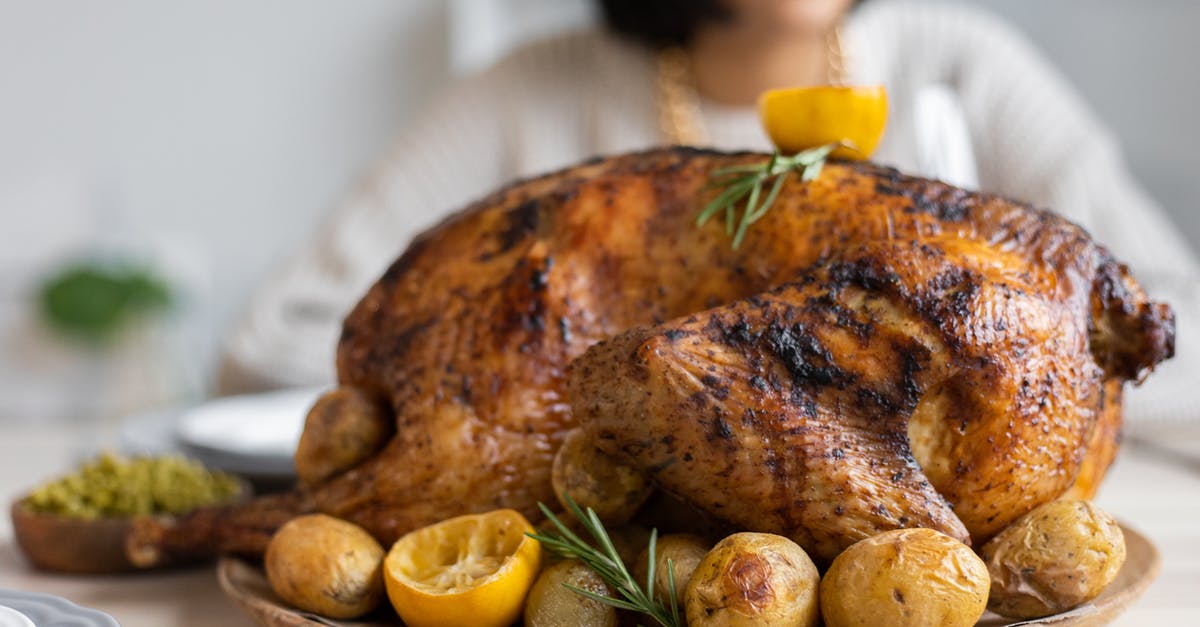 How long to roast a whole goose? - Palatable roasted turkey with potatoes and lemon on wooden round tray placed on table for celebrating Thanksgiving Day