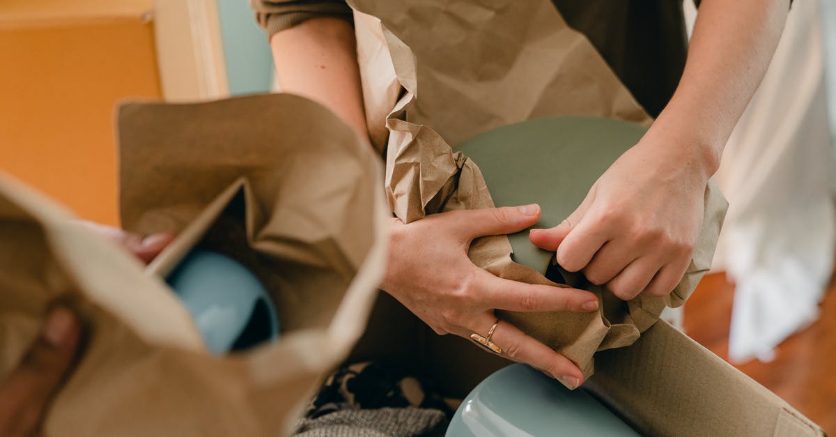 How many ceramic knives do I want? - Crop unrecognizable person packing ceramic tableware in parchment