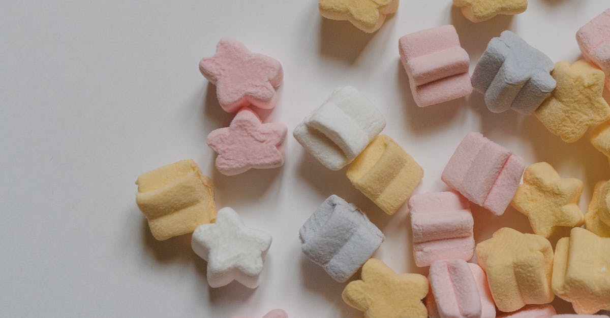 How many grams of gelatin are in stock/broth? - Top view yummy multicolored marshmallows scattered in shape of stars scattered on corner of white table