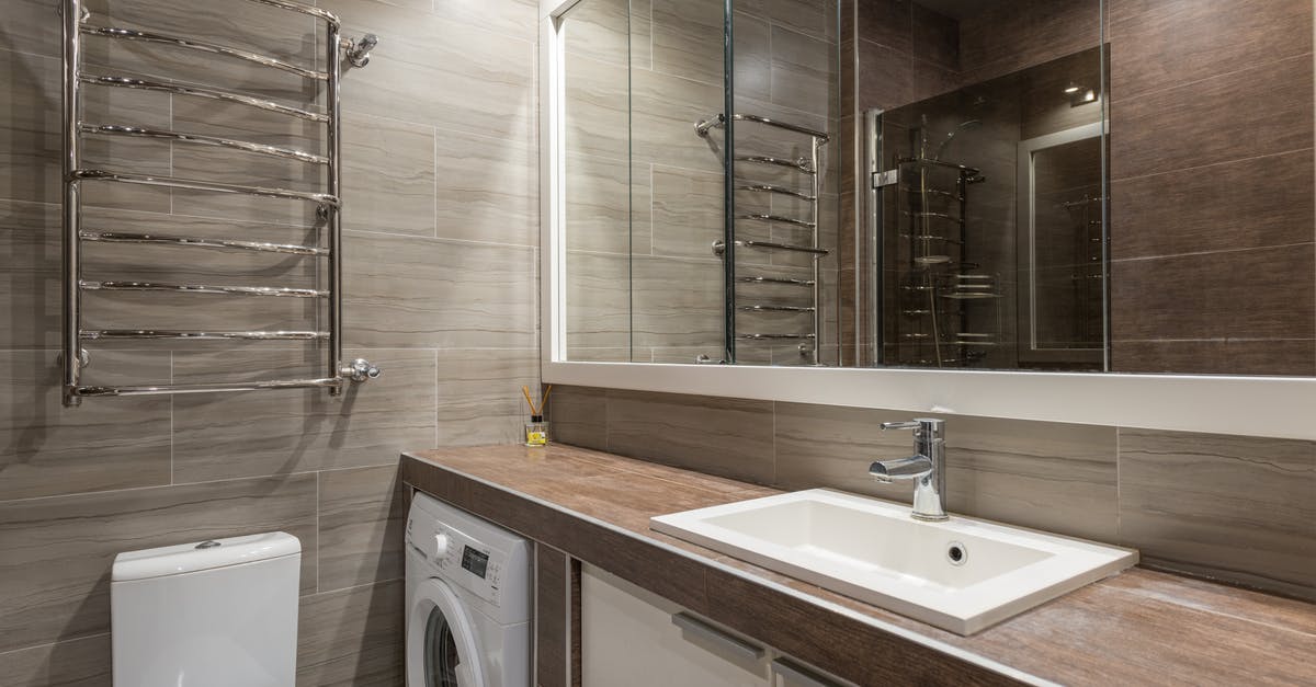 How many wash cycles should I aim for when washing brown rice? - White ceramic toilet bowl and sink in contemporary bathroom with big mirror reflecting brown tiled walls