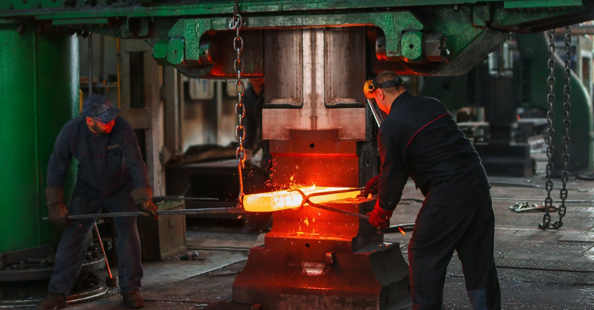 How much could I safely heat a content-less cast-iron pan? - Two Men Holding Two Gray Metal Tools