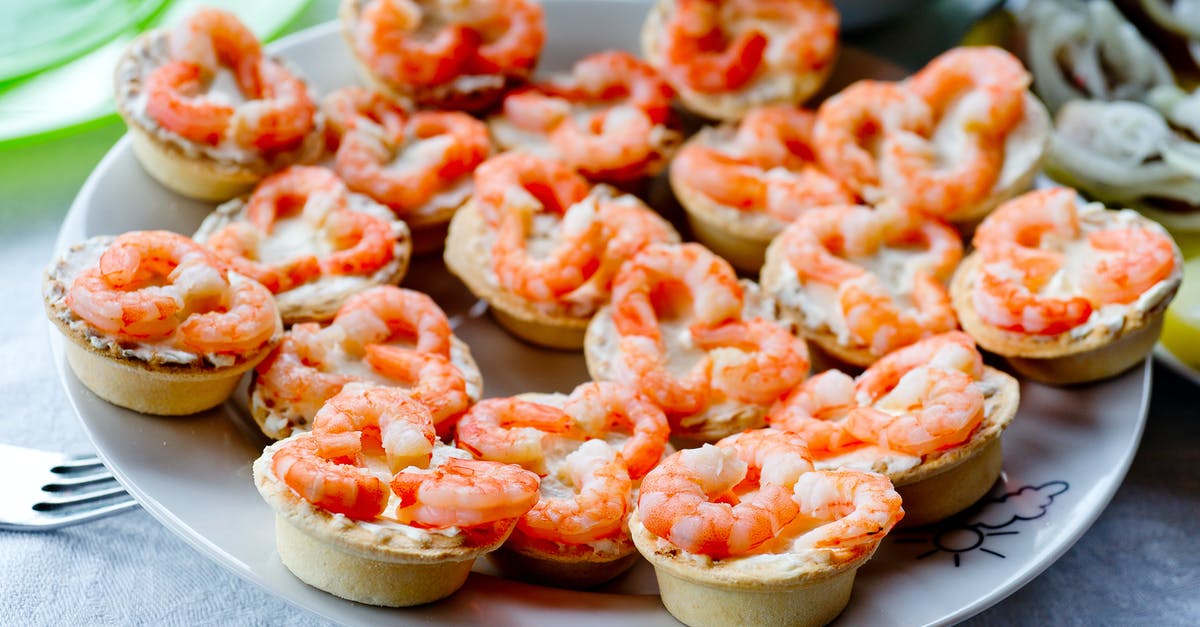 How much of a shrimp is meat? - Peeled red boiled shrimps on tartlets on white plate on table in daylight in bright room