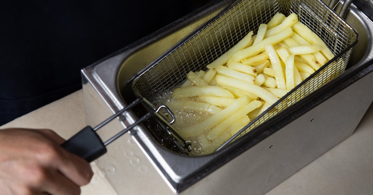 How much oil should you use when stir frying a single portion? - Photo of a Person's Hand Deep Frying French Fries