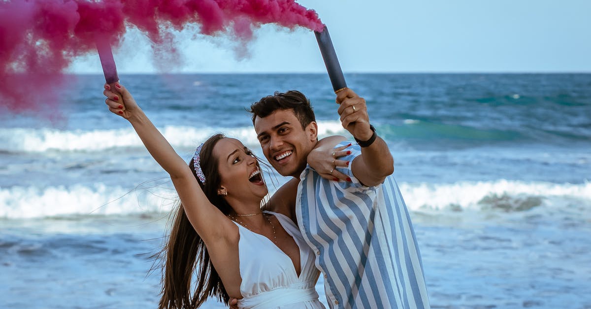 How much smoke to expect from making a roux? - Cheerful pregnant couple in trendy apparels holding bomb of pink colorful smoke embracing near wavy ocean