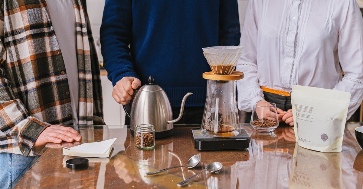 How much vinegar should I use when making Salsa? - Man in Blue Sweater Standing Beside Table With Clear Drinking Glass and Pitcher