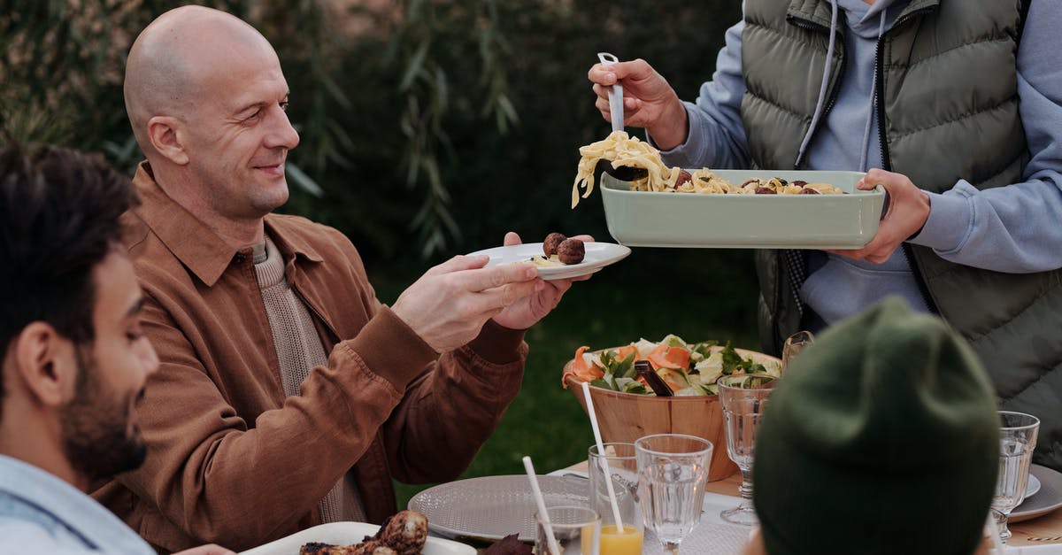 How much water to put in my pasta pot? - Unrecognizable woman serving delicious pasta with meatballs to man during dinner