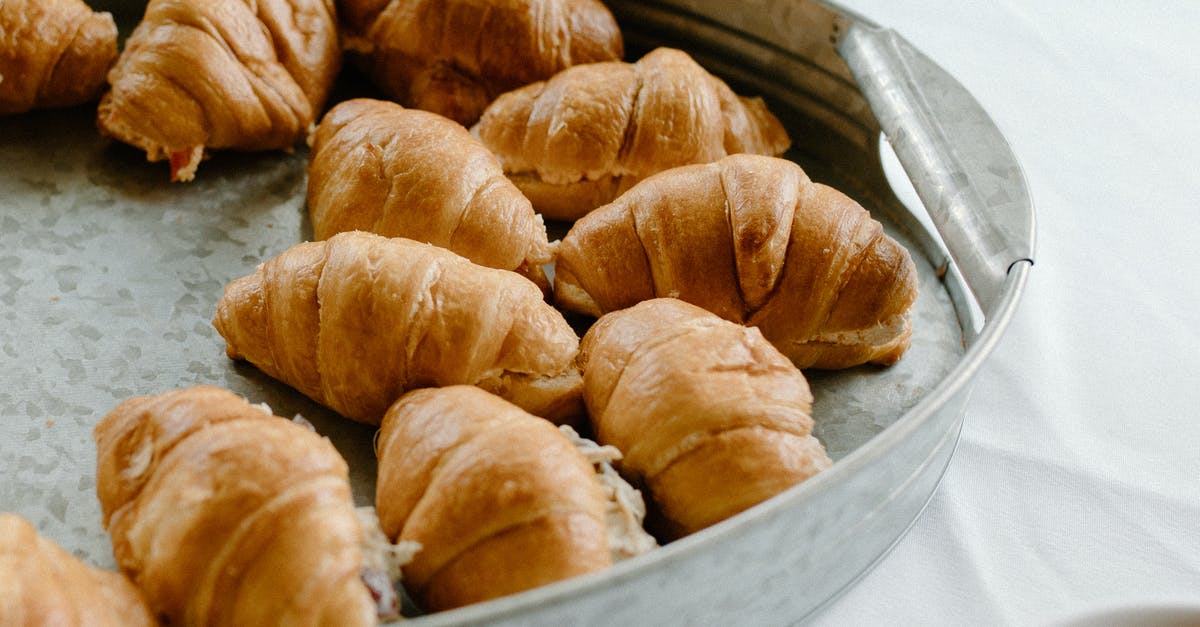 How prepared should a baked dessert be before a long transport? - From above of baked croissants in tin tray prepared for dessert and placed on white table How prepared should a baked dessert be before a long transport? - From above of baked croissants in tin tray prepared for dessert and placed on white table