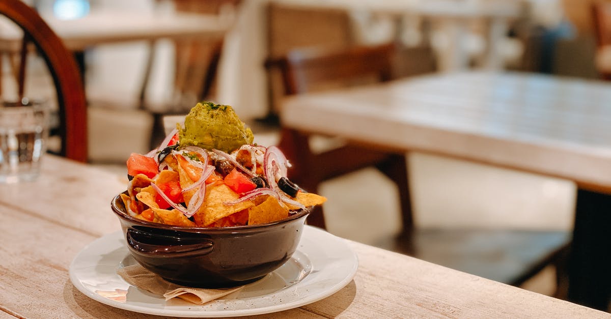 How salty is olive brine? - Tasty fresh nachos with guacamole in bowl on wooden table in Mexican restaurant