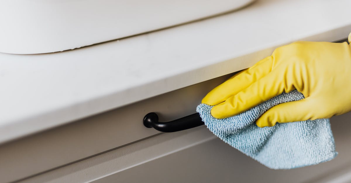 How should I handle chiles without gloves? - From above of crop faceless person in yellow gloves cleaning handle of cabinet with microfiber cloth in modern bright bathroom