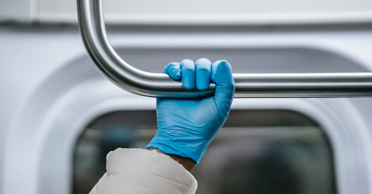 How should I handle chiles without gloves? - Crop anonymous African American person in warm clothes and protective glove grabbing overhead handle while riding metro train during coronavirus outbreak