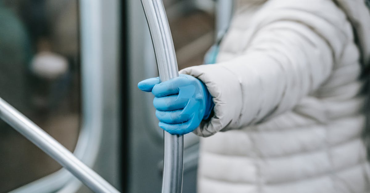 How should I handle chiles without gloves? - Side view crop person in outerwear and latex gloves holding handle and riding underground train during coronavirus epidemic