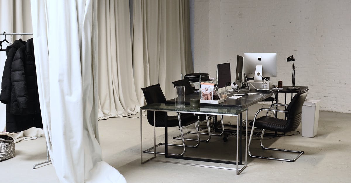 How should I manage my fridge? - Interior of conference room with modern personal computers placed on table with clothes hanging on rail