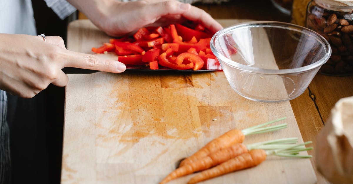How should I store a cut bell pepper? - Crop unrecognizable woman cutting bell pepper in kitchen
