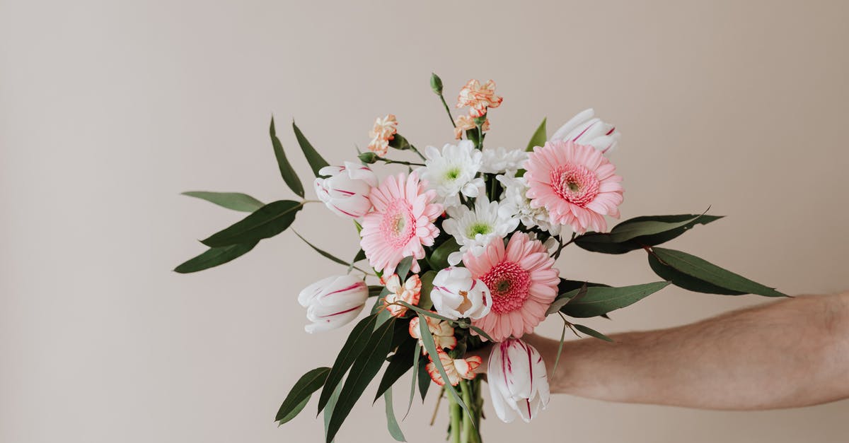 How should I store herb butter? - Unrecognizable male holding bunch of fresh chamomiles cloves and gerberas during making tender spring composition against beige background